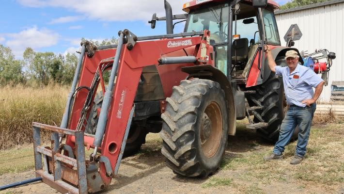 Tim, Hay Producer in Scenic Rim Person wearing dark long pants and light blue shirt standing in front of a large tractor
